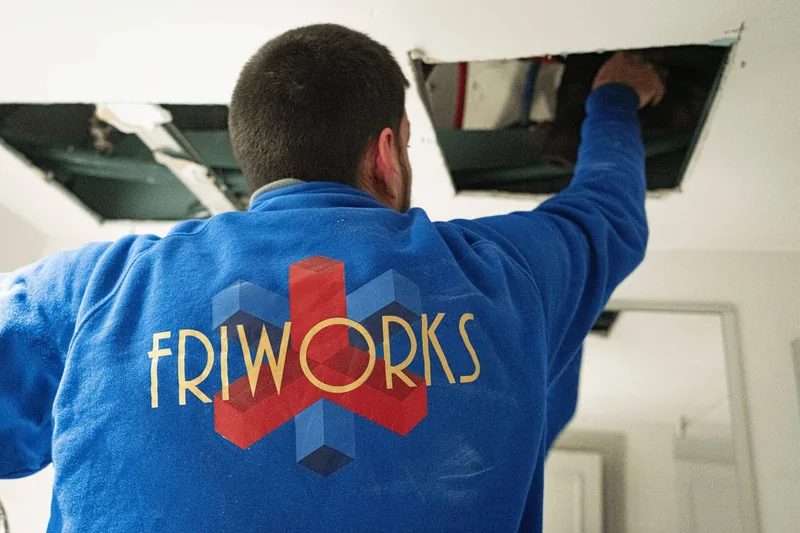 Técnico de Friworks trabajando sobre un falso techo durante una instalación de climatización